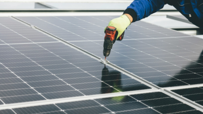 A photo of solar panels with someone drilling