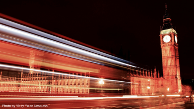 A timelapse photo of the UK Parliament building with car lights blurring past
