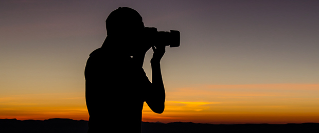 photographer silhouetted against a sunset