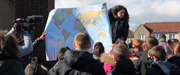 crowd of school children being shown a map of the world